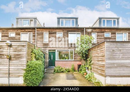 Modernes zweistöckiges Haus mit Holzfassade und Dachfenster, umgeben von grünen Pflanzen. Stockfoto