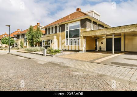 Ein modernes zweistöckiges Vorstadthaus mit großen Fenstern, einer Garage und einem gepflegten Hof unter klarem blauen Himmel. Stockfoto