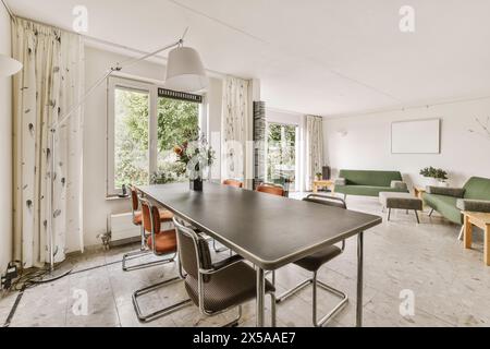 Modernes Wohnzimmer, das nahtlos in einen stilvollen Essbereich mit Tageslicht und Blick auf das Grün integriert ist. Stockfoto