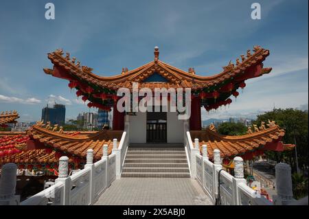 Lebendiges Bild einer goldenen Drachenskulptur auf einem traditionellen chinesischen Gebäudedach, das mit roten Laternen vor einem klaren blauen Himmel geschmückt ist. Stockfoto