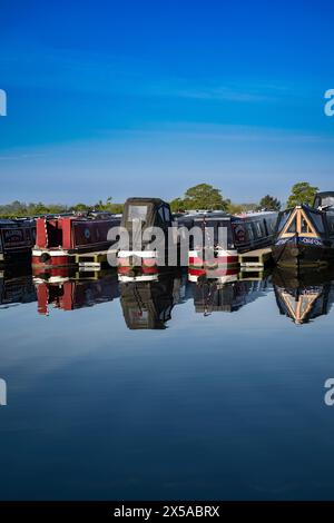 Dunchurch Pools Marina, Warwickshire, Oxford Canal – Schmalboote am Sommermorgen in ruhiger Umgebung vor einem klaren blauen Himmel Stockfoto