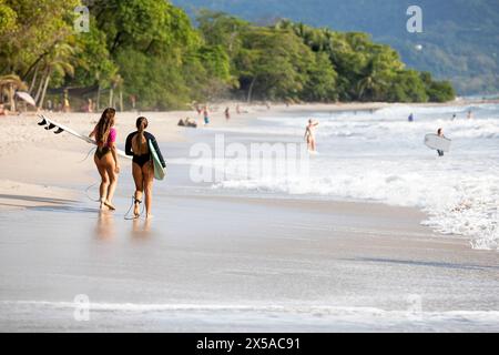 Zwei weibliche Surferinnen wandern während der weihnachtsferien am Sandstrand Playa Santa Teresa auf der Halbinsel Nicoya, Costa rica Stockfoto