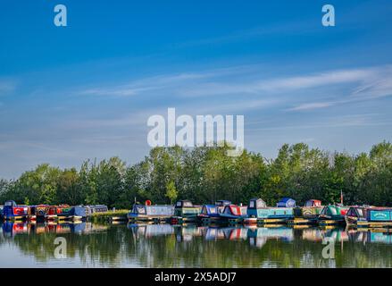 Dunchurch Pools Marina, Warwickshire, Oxford Canal – Schmalboote am Sommermorgen in ruhiger Umgebung vor einem klaren blauen Himmel Stockfoto