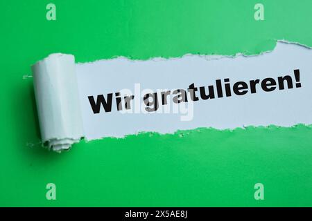 Konzept von Wir Gratulieren Text geschrieben in zerrissenem Papier. Stockfoto