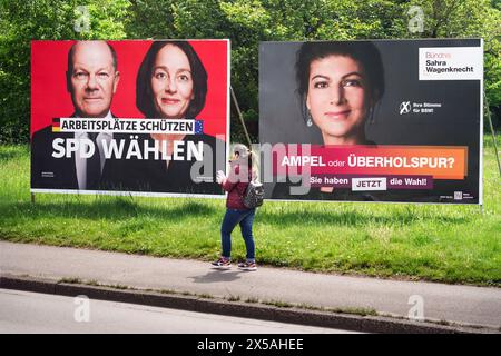 Dortmund, 8,5.2024: Eine Person geht entlang der Wahlplakate zur Europawahl am 9,6.2024. Links: Plakat der SPD mit Bundeskanzler Olaf Scholz und der deutschen EU-Spitzenkandidatin Katarina Barley. Rechts: Plakat der Partei BSW Bündnis Sahra Wagenknecht mit Ihrer Spitzenkandidatin Sahra Wagenknecht --- Dortmund, 8. Mai 2024: Eine Person läuft auf den Wahlplakaten für die Europawahlen am 9. Juni 2024. Links: SPD-Poster mit Bundeskanzler Olaf Scholz und der deutschen Spitzenkandidatin Katarina Barley. Rechts: Poster der BSW Alliance Sahra Wagenknecht mit ihrer Spitzenkandidatin Sahra Stockfoto