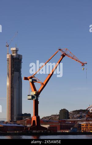 göteborg, Schweden - 4. Februar 2023: Bau des Hochhauses Karlatornet. Betonrahmen halb mit Fenstern bedeckt. Der alte Hafenkran im Nebel Stockfoto