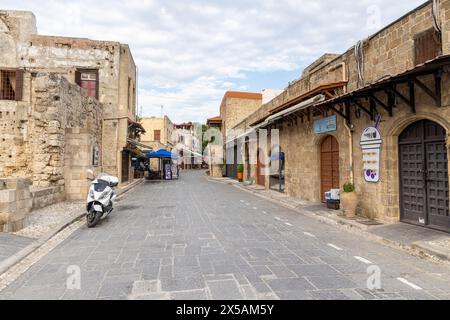 Rhodos, Griechenland - 12. Juni 2023: Leere Straße in der Altstadt mit Steinhäusern und geparktem Motorrad. Keine sichtbaren Personen Stockfoto