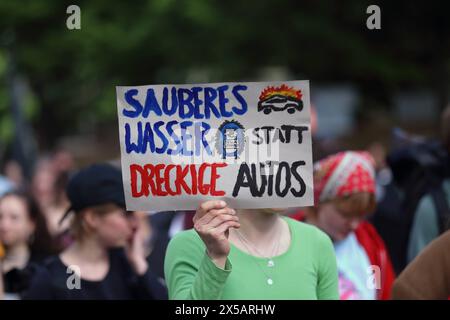 Eine Demonstrantin mit Schild sauberes Wasser statt dreckige Autos während einer Demonstration gegen die geplante Erweiterung der Tesla Gigafactory in Grünheide Mark, Potsdam, 8. Mai 2024. Demo gegen Tesla in Potsdam *** Demonstration mit einem Schild sauberes Wasser statt schmutziger Autos während einer Demonstration gegen den geplanten Ausbau der Tesla Gigafactory in Grünheide Mark, Potsdam, 8. Mai 2024 Demonstration gegen Tesla in Potsdam Stockfoto