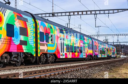 Eine Zürcher S-Bahn der Linie S24 (S-Bahn 24) vom Typ SBB Rabe 514 fährt in den Bahnhof Bassersdorf ein. Der Zug trägt die ZVV-Werbung mit dem Titel ' Stockfoto