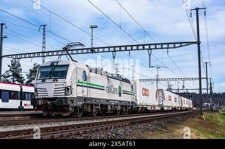 Eine Vectron AC der Logistikfirma railCare zieht Güterwagen des Lebensmitteldetailhändlers Coop und fährt durch den Bahnhof von Bassersdorf im Zürcher Stockfoto