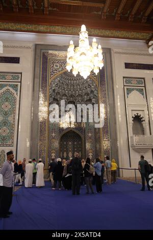 Sultan Qaboos Grand Mosque Interior Touristen stehen auf dem Schutzteppich des Mihrab Muscat Oman Stockfoto