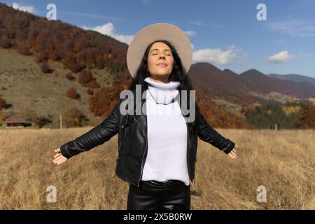Junge Frau, die die schöne Herbstlandschaft vor sich spürt. Stockfoto