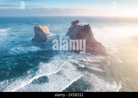 Blick aus der Vogelperspektive auf den malerischen Sonnenaufgang, der über Wharariki Beach und Bogenway Island auf Tasmansee am Westen des cape Farewell in Neuseeland scheint Stockfoto