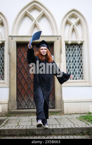 Glücklicher Absolvent. Ich gratulierte den Absolventen von University.graduate Mädchen im Mantel hält in Händen Abschlussdiplom Stockfoto