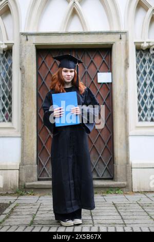 Glücklicher Absolvent. Ich gratulierte den Absolventen von University.graduate Mädchen im Mantel hält in Händen Abschlussdiplom Stockfoto