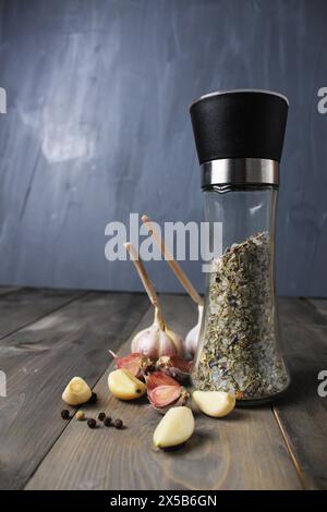 Geschälte Knoblauchwürze Pfefferkörner in einer Mühle auf grauem Hintergrund Nahaufnahme. Stillleben. Stockfoto