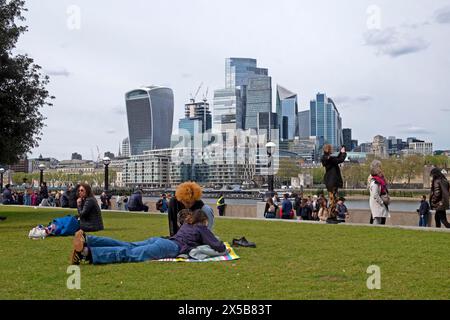 Menschen Touristen entspannen auf Gras an der Tower Bridge, City of London Blick auf Wolkenkratzer von More London Riverside im Frühjahr 2024 UK KATHY DEWITT Stockfoto