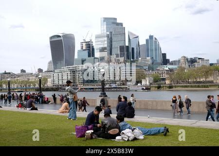 Menschen Touristen sitzen auf dem Rasen an der Thames Tower Bridge, City of London Blick auf Wolkenkratzer von mehr London Riverside in der britischen Stadt KATHY DEWITT Stockfoto