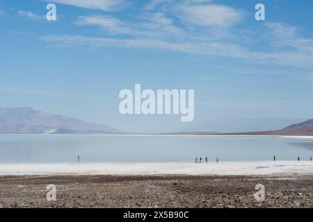 Menschen laufen auf den Salzebenen des Bad Water Basin, wo sich der Lake Manly nach sintflutartigen Regenfällen bildete Stockfoto