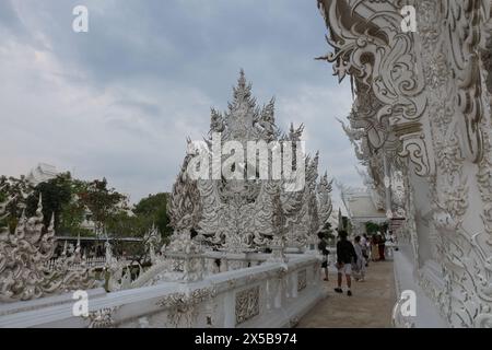 Komplizierte und aufwendige Schnitzereien am Weißen Tempel in Thailand mit Touristen, die herumlaufen Stockfoto