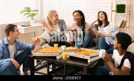 Eine Gruppe von Teenagern sitzt an einem Tisch und isst Pizza Stockfoto
