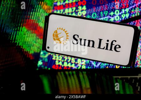 Krakau, Polen. Mai 2024. In dieser Fotoabbildung wird das Sun Life Financial Inc Logo auf einem Smartphone-Bildschirm vor einem Computerbildschirm angezeigt, und seine Reflexionen zeigen eine Illustration der Börsennummern. Das Unternehmen veröffentlicht seine Ergebnisse für das 1. Quartal – Krakau, Polen, am 8. Mai 2024. (Foto: Dominika Zarzycka/SIPA USA) Credit: SIPA USA/Alamy Live News Stockfoto