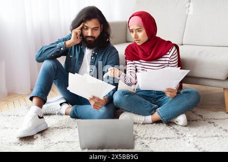 Junge Paare, die Finanzdokumente in ihrem Wohnzimmer überprüfen Stockfoto