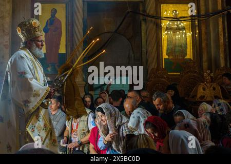 Ein orthodoxer Geistlicher und Gläubige, die während eines besonderen Gebets nach der Feuerzeremonie gesehen wurden. Die Heilige Feuerzeremonie wird jedes Jahr vor Ostern von orthodoxen Kirchen in der Grabeskirche in Jerusalem gefeiert. Dieses spirituelle und religiöse Ereignis ist eines der wichtigsten Rituale des orthodoxen Christentums, und viele Pilger kommen aus der ganzen Welt, um es zu bezeugen. Während der Zeremonie betet der griechische Patriarch in die Ädikulae, wo sich das Grab Jesu befindet, und betet, bis das heilige Feuer vom Heiligen Geist angezündet wird. Die Menschenmassen in der Kirche warten draußen Stockfoto