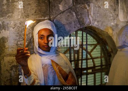 4. Mai 2024, Jerusalem, Israel: Eine äthiopische Frau hält eine Kerze während der Heiligen Feuerzeremonie der Äthiopisch-orthodoxen Kirche in Jerusalem. Die Heilige Feuerzeremonie wird jedes Jahr vor Ostern von orthodoxen Kirchen in der Grabeskirche in Jerusalem gefeiert. Dieses spirituelle und religiöse Ereignis ist eines der wichtigsten Rituale des orthodoxen Christentums, und viele Pilger kommen aus der ganzen Welt, um es zu bezeugen. Während der Zeremonie betet der griechische Patriarch in die Ädikulae, wo sich das Grab Jesu befindet, und betet, bis das heilige Feuer von der Heiligen SPIR angezündet wird Stockfoto