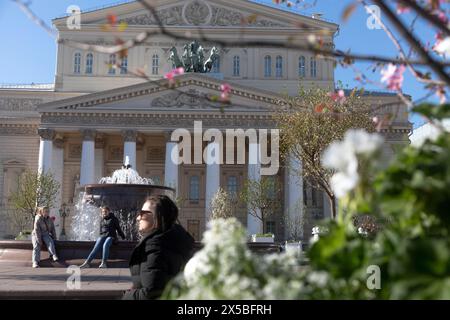 Moskau, Russland. Mai 2024. Blühende Bäume mit jungem Laub auf dem Hintergrund der Fassade des Bolschoi-Theaters auf dem Teatralnaja-Platz im Zentrum von Moskau, Russland Stockfoto