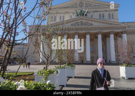 Moskau, Russland. Mai 2024. Blühende Bäume mit jungem Laub auf dem Hintergrund der Fassade des Bolschoi-Theaters auf dem Teatralnaja-Platz im Zentrum von Moskau, Russland Stockfoto