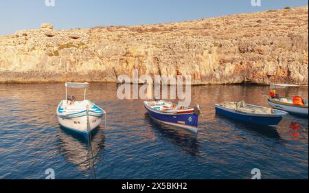 Blue Grotto, Malta - 22. August 2019: Blue Grotto Harbour. Kleine Vergnügungs- und Fischerboote liegen an einem sonnigen Morgen vor alten Befestigungsanlagen Stockfoto