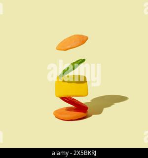 Gummibonbons in Form eines Cheeseburgers auf hellbeigem Hintergrund. Minimales Junk Food-Konzept. Stockfoto