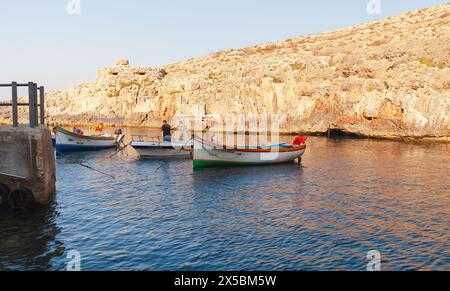 Blue Grotto, Malta - 22. August 2019: An einem sonnigen Morgen werden Holzfischboote vor alten Befestigungsanlagen vor Anker gebracht. Blick auf die Küste des Blue Gr Stockfoto