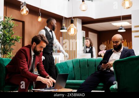 Zwei Geschäftsleute arbeiten im Loungebereich, elegante Hotelatmosphäre mit wichtigen Gästen in Anzügen. Unternehmer bereiten sich auf eine Rede auf der internationalen offiziellen Konferenz vor. Stockfoto