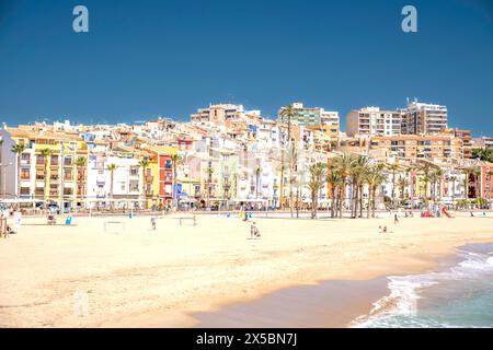 La Vila Joiosa, Spanien - 24. April 2024: Blick auf die wunderschöne Küstenstadt Villajoyosa. Strandpromenade mit farbenfrohen Häusern, Leute, die sich im Freien entspannen Stockfoto