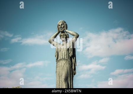 Madrid, Spanien. 1. Mai 2024 Jacinto Benavente Denkmal für eine Frau, die eine Maske im Gesicht trägt. Weibliche Statue in Bronze vor blauem Himmel. Power-Konzept für Frauen, Stockfoto