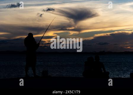 Salvador, Bahia, Brasilien - 13. April 2019: Fischer werden bei Sonnenuntergang in Ponta do Humaita in der Stadt Salvador, Bahia, in Silhouette gesehen. Stockfoto