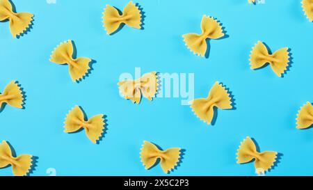 Ungekochte Pasta mit Fliege, farfalle auf blauem Hintergrund in einem dekorativen Muster Stockfoto
