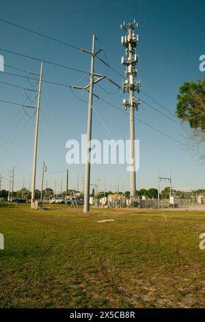 Vertikale Ansicht bei Sonnenuntergang der elektrischen Umspannstation mit Hochspannungsleitungen in St. Petersburg, Florida. Nutzfahrzeuge. Blick auf grünes Gras und blauer Himmel. Stockfoto