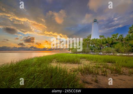 'Golden Hour Glow: Wenn die Sonne hinter dem MarkusLeuchtturm untergeht und ein warmes Licht über die Gräser und Palmen wirft. Stockfoto