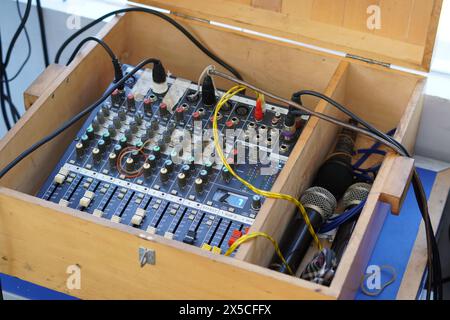 Der Audio-Mixer, der mit mehreren Kabeln zusammen mit dem Mikrofon verwendet wird, befindet sich in einer Holzbox Stockfoto