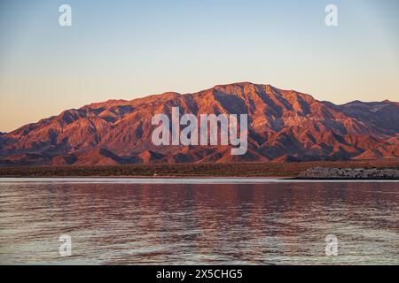 Malerische Landschaft mit ruhigem Wasser und zerklüfteten Bergen bei einem orange-roten Sonnenuntergang in Bahia de los Angeles, Baja California, Mexiko Stockfoto