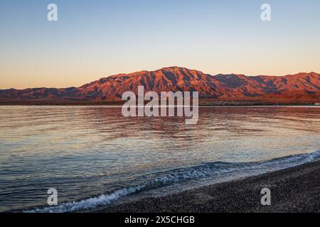 Malerische Landschaft mit ruhigem Wasser und zerklüfteten Bergen bei einem orange-roten Sonnenuntergang in Bahia de los Angeles, Baja California, Mexiko Stockfoto