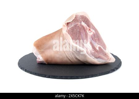 Frischer roher Schweinshaxe auf schwarzem Steinteller auf weißem Hintergrund Stockfoto