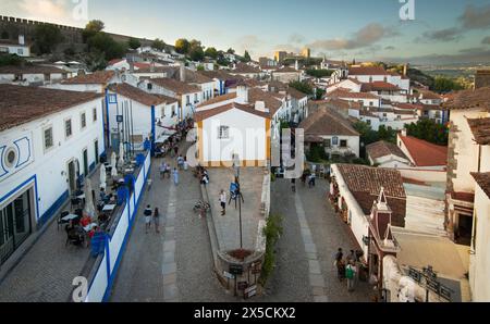 Óbidos, Portugal. Blick nach Norden über den Padrao Camoniano Platz vom Porta da Vila (doppelwandiges Südtor). Die Straße links ist Rua Direita und Rua Josefa de Obidos auf der rechten Seite. Die mittelalterliche Stadt, die seit 308 v. Chr. bewohnt wurde, ist eine der am besten erhaltenen klassischen Mauersiedlungen Portugals mit einer heutigen Bevölkerung von über 3.000 Einwohnern, 100 km nördlich der portugiesischen Hauptstadt Lissabon an der Atlantikküste. Stockfoto