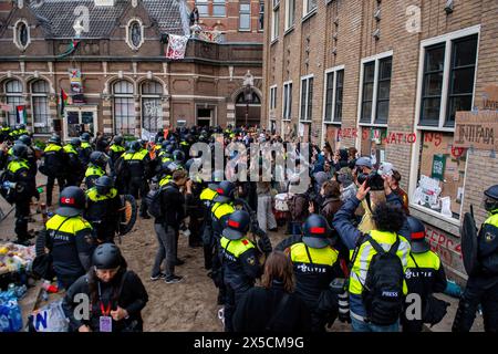 Umgeben von der Polizei halten Studenten ihre Hände hoch, während die Polizei Barrikaden durchbricht, um eine propalästinensische Studentenbesetzung an der Universität Amsterdam zu beenden. Die Polizei demontiert einen propalästinensischen Studentenprotest und eine Besatzung an der Universität Amsterdam mit Schlagstöcken, Schilden und Erdbewegungsgeräten. Die Konfrontation folgte, als die Demonstranten sich unter Spannungen für die palästinensische Solidarität versammelten, intervenierten die Strafverfolgungsbehörden, um die Menge zu zerstreuen, was zu Zusammenstößen und Festnahmen führte. (Foto: Michael Currie/SOPA Images/SIPA USA) Stockfoto