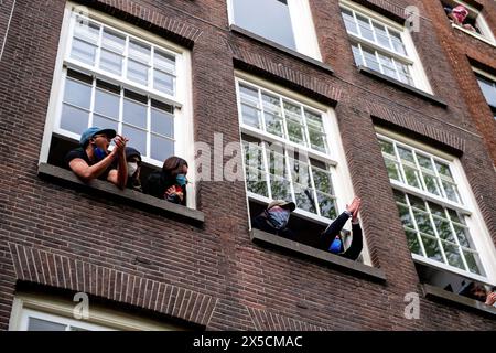 Amsterdam, Niederlande. Mai 2024. Unterstützer schreien aus den Fenstern der Studentenbewohner, als die Polizei Barrikaden durchbrach, um eine propalästinensische Studentenbesetzung an der Universität Amsterdam zu beenden. Die Polizei demontiert einen propalästinensischen Studentenprotest und eine Besatzung an der Universität Amsterdam mit Schlagstöcken, Schilden und Erdbewegungsgeräten. Die Konfrontation folgte, als die Demonstranten sich unter Spannungen für die palästinensische Solidarität versammelten, intervenierten die Strafverfolgungsbehörden, um die Menge zu zerstreuen, was zu Zusammenstößen und Festnahmen führte. Quelle: SOPA Images Limited/Alamy Live News Stockfoto