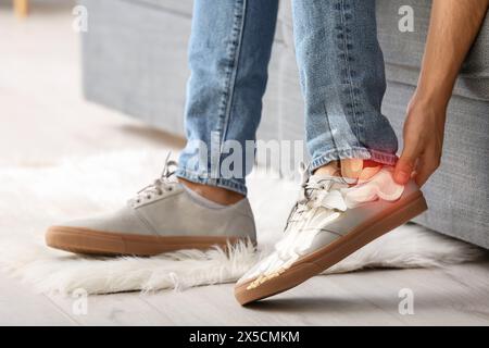 Junger Mann fühlt sich weh, weil er High Heels trägt Stockfoto