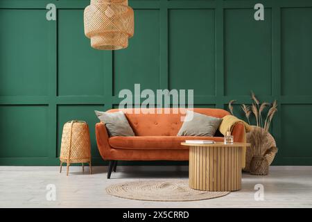 Interieur des stilvollen Wohnzimmers mit rotem Sofa, Tisch und Lampen Stockfoto